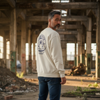 Man wearing a white sweatshirt with a logo in an industrial setting